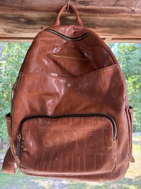 brown leather steve madden backpack Women's Riggs Bag - Distressed Featuring dome stud details and knotted fringe decals on a gusset with rounded bottom metal aglets Steve Madden Brown and Cream